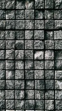 Textured gray stone wall with square blocks arranged in a grid pattern Stock Photos