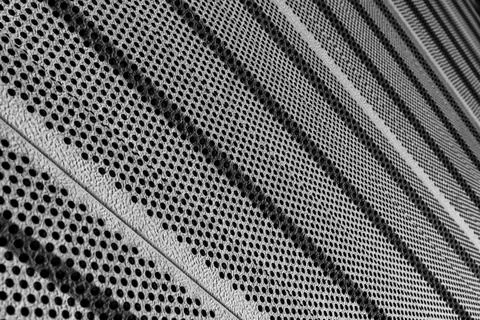 Textured metal surface with circular perforations in a modern architectural Stock Photos