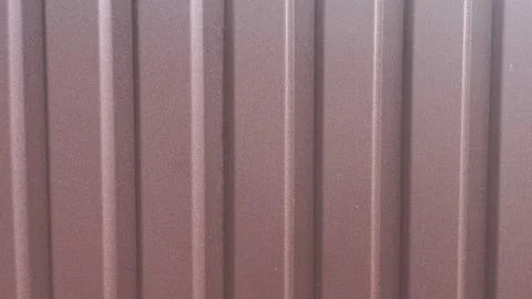 Textured metal surface with vertical lines and muted maroon color Stock Photos