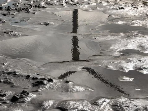 Textured mud flat with shallow reflective water 스톡 사진