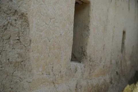 Textured mud wall with small rectangular window opening in a rural village setti Stock Photos
