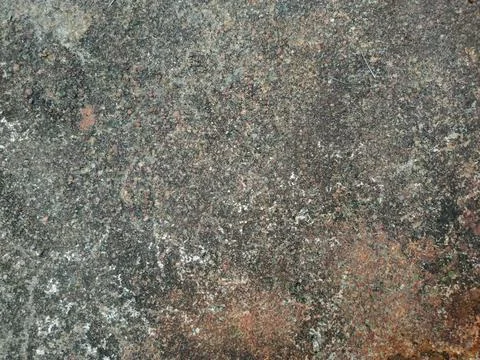 A textured overhead view shows a weathered stone surface speckled with dark.. Stock Photos