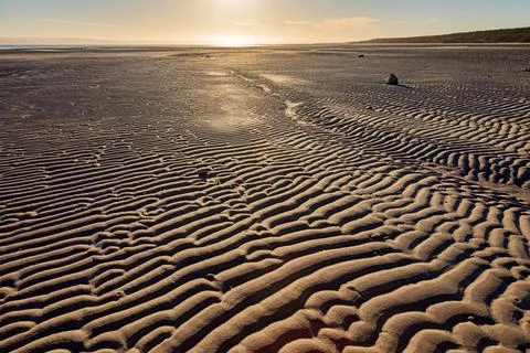 Textured pattern of Ripples in beach sand at sunrise Stock Photos