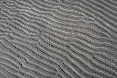 Textured pattern on a sand surface along the shore. 库存照片