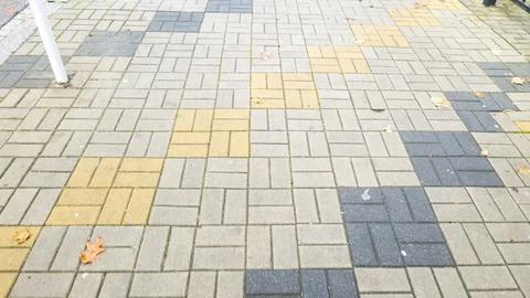 Textured pavement with geometric patterns in gray, yellow, and black colors. Foto stock