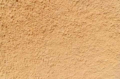 Textured peach stucco wall surface with rough plaster finish Stock Photos