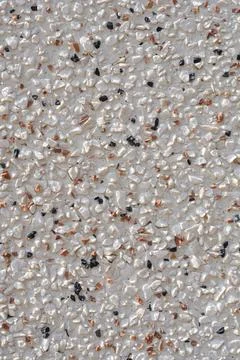 Textured pebble dash wall surface with white orange and black stones Stock Photos