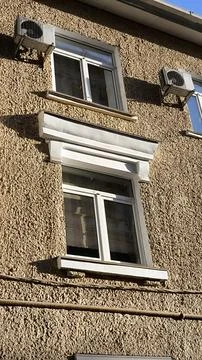Textured plaster building facade with windows and air conditioning units. Фото