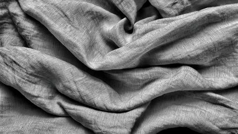 Textured silver grey raw silk fabric drapery casting elegant shadows in a d.. Stock Photos