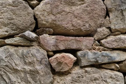 Textured stone wall composed of various sizes and shapes of natural stones in Stock Photos