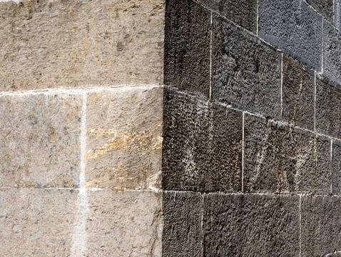 Textured stone wall with contrasting light and dark blocks Stock Photos