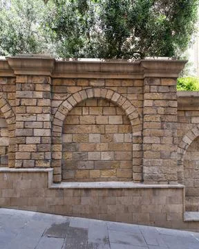 Textured stone wall featuring multiple arches creates a tranquil atmosphere in Stock Photos