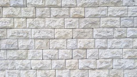 Textured stone wall with rectangular light grey beige blocks arranged Stock Photos