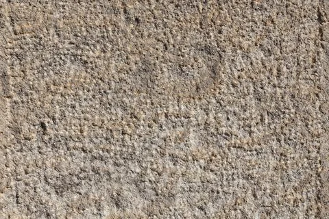 Textured stone wall showcasing ancient carvings under bright sunlight in an.. Stock Photos