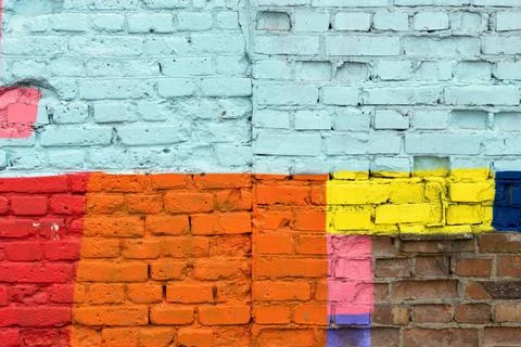 Textured surface of a brick wall with multicolored spots Foto stock
