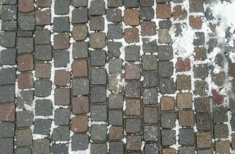 A textured surface of cobblestones arranged in a pattern, lightly dusted with 스톡 사진