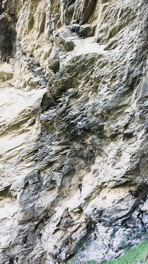 The textured surface of a rock features natural layers and striations, creating Video stock 307426296