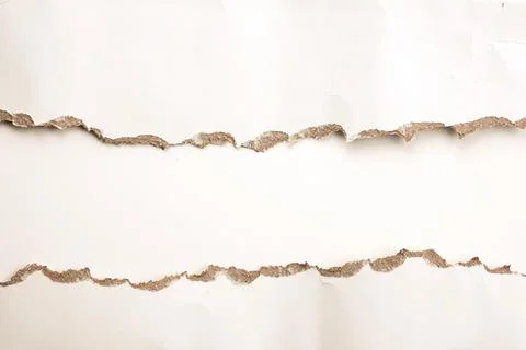 A textured surface shows torn edges of white paper, revealing a light brown.. Stock Photos