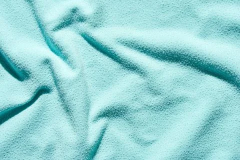 Textured teal fabric surface with soft wrinkles and subtle light reflections 스톡 사진