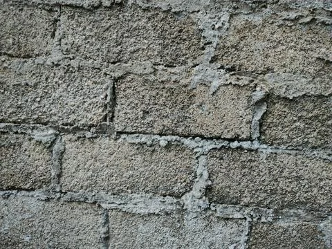 A textured wall built with gray concrete blocks shows visible mortar lines .. Stock Photos