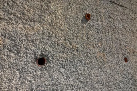 A textured wall displaying two small circular holes for drainage Stock Photos