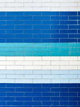 A textured wall featuring rectangular tiles in a mosaic of various blue and.. Stock Photos