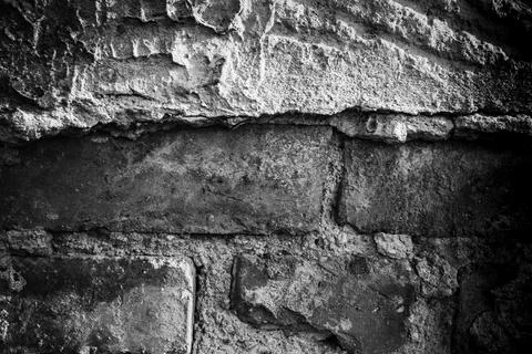 Textured wall featuring rough stone and plaster surfaces in monochrome tones Stock Photos