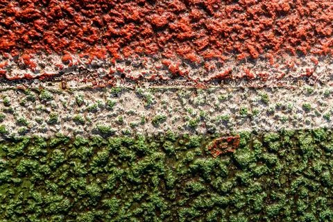 Textured wall with layers of red, white, and green paint in a close-up view Stock Photos