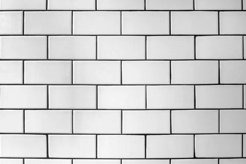 The textured wall is lined offset with white glossy ceramic tiles. Stock Photos