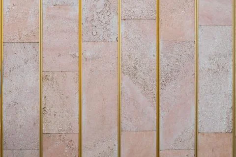 Textured wall lined with shell rock tiles and decorated with brass strips. Stock Photos