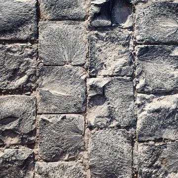Textured wall made of gray square stone blocks, showcasing modern masonry and Stock Photos