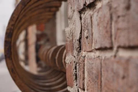A textured wall of red brick with a rusty iron fence in the background, going Stock Photos