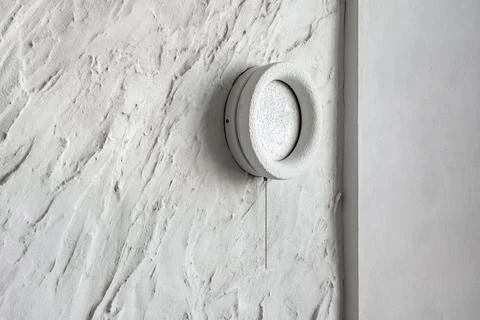 Textured white plaster wall with wall mounted light Foto stock