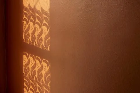 Textured Window Shadows Casting Artistic Patterns on Orange Painted Wall Surface Stock Photos