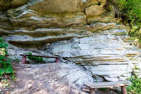 Textures of various stone layers on cliff. Benches in rest place on hiking tr Stock Photos