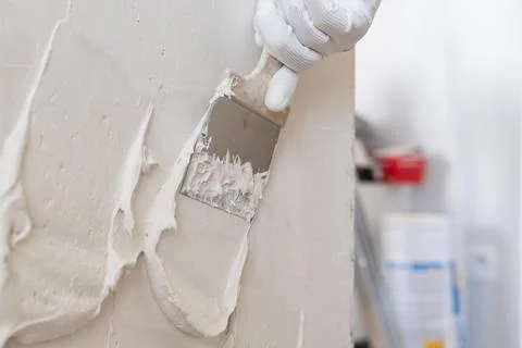 Texturing wall surface with stainless steel trowel in interior construction Stock Photos