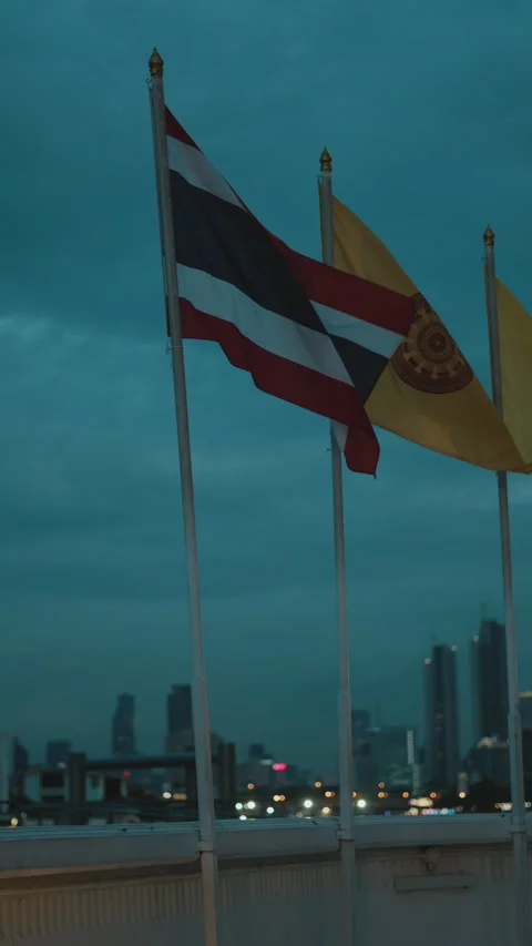 Thai and buddhist flags waving in the wind against the bangkok city skyline 스톡 동영상 346275599