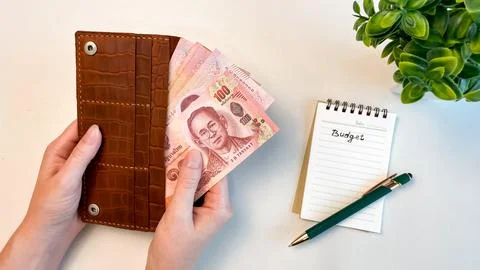 Thai banknotes in a wallet next to a notebook Stock Photos