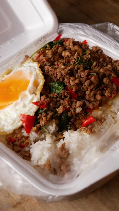 Thai basil stir-fried minced pork with crispy fried egg over steamed rice in a Stock Footage 348130600