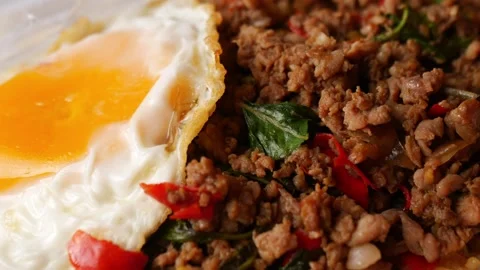 Thai basil stir-fried minced pork with crispy fried egg over steamed rice in a Stock Footage 348130617
