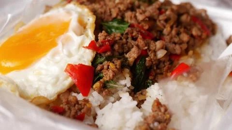 Thai basil stir-fried minced pork with crispy fried egg over steamed rice in a Stock Footage 348336670