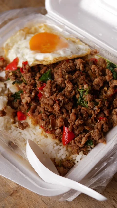 Thai basil stir-fried minced pork with crispy fried egg over steamed rice in a Stock Footage 348336699