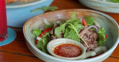 Thai beef salad with spicy dressing on wooden table. Fresh greens, Stock Footage 312000147