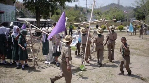Thai Boy Scout camp activity joyful boys and girls teams carry wooden catapult Stock Footage 157281707