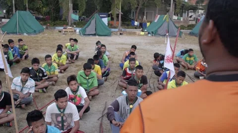 Thai Boy Scout camp meeting teacher talk to students sitting on the grass Stock Footage 157441041