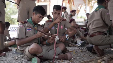 Thai Boy Scout in uniform making wooden catapult join sticks tie with a rope Stock Footage 157442061