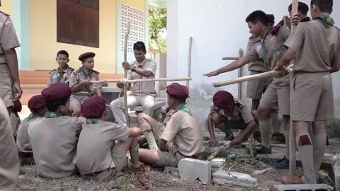 Thai Boy Scout in uniform making wooden catapult teacher shows how to tie rope Stock Footage 157442503