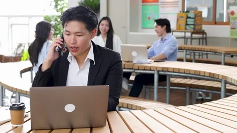 Thai Businessman Talking on Smartphone While Working on Laptop in Bangkok Stock Footage 344724012