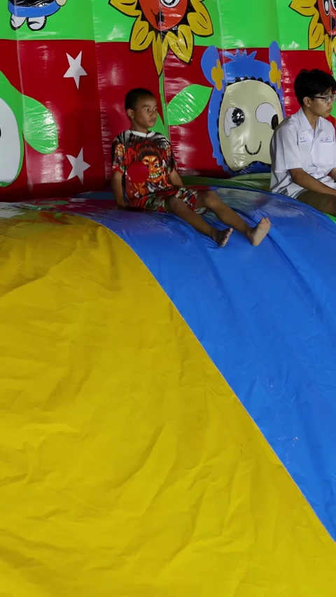 Thai Children Playing and Jumping on a Colorful Inflatable Bounce House Stock Footage 328812910