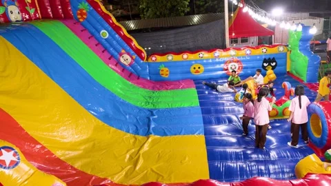 Thai Children Playing on Large Inflatable Slide at Night Carnival Stock Footage 327688638